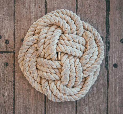 A symmetrical knot with thick rope lying on weathered wood.
